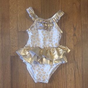 Elegant Gold and White One Piece Swimwear with Ruffle Accents By Candle Sticks
